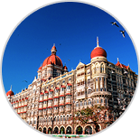 View of the Taj Mahal Palace Hotel in Mumbai, India, showcasing its stunning architecture with red domes and intricate details under a clear blue sky, symbolizing heritage and luxury in Mumbai.