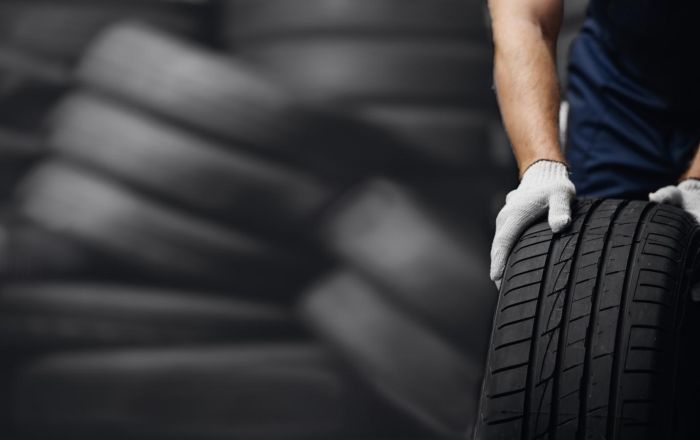 Mechanic handling a car tire in a workshop, symbolizing modernizing a multi-generational family office with unified systems, automation, and real-time financial intelligence for digital transformation.